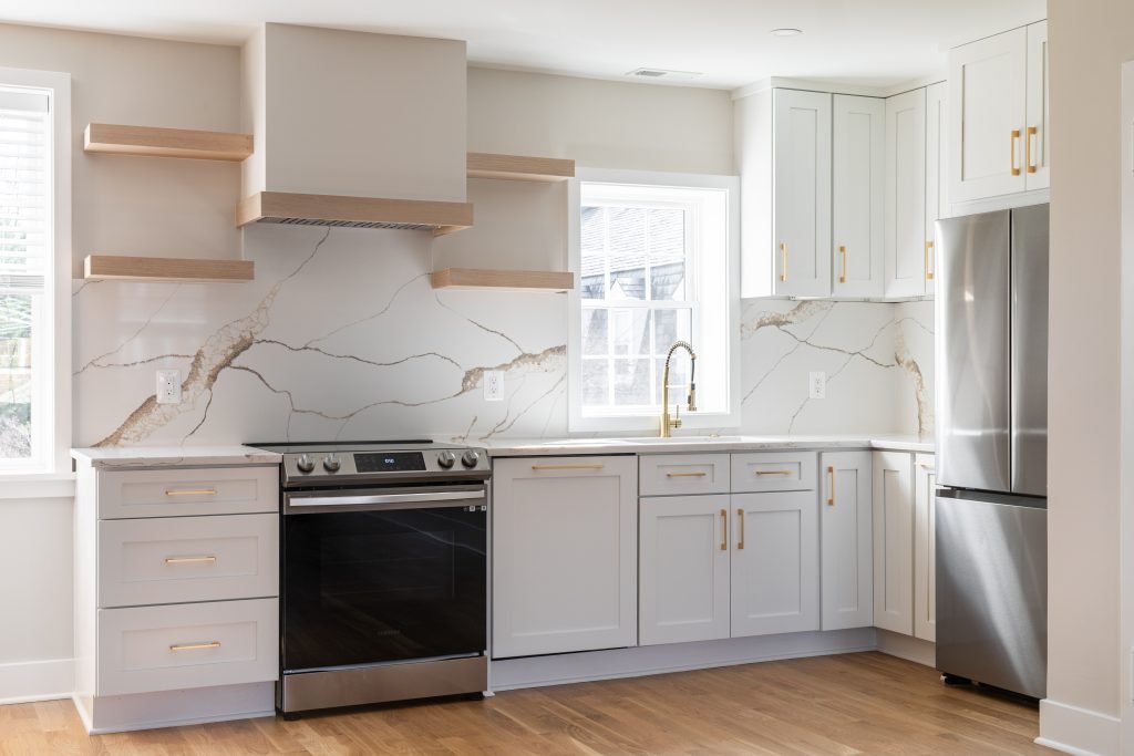 Modern kitchen remodel with white cabinets, stone backsplash, stainless steel appliances, and updated finishes for the home remodeling process