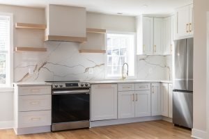 Modern kitchen remodel with white cabinets, stone backsplash, stainless steel appliances, and updated finishes for the home remodeling process