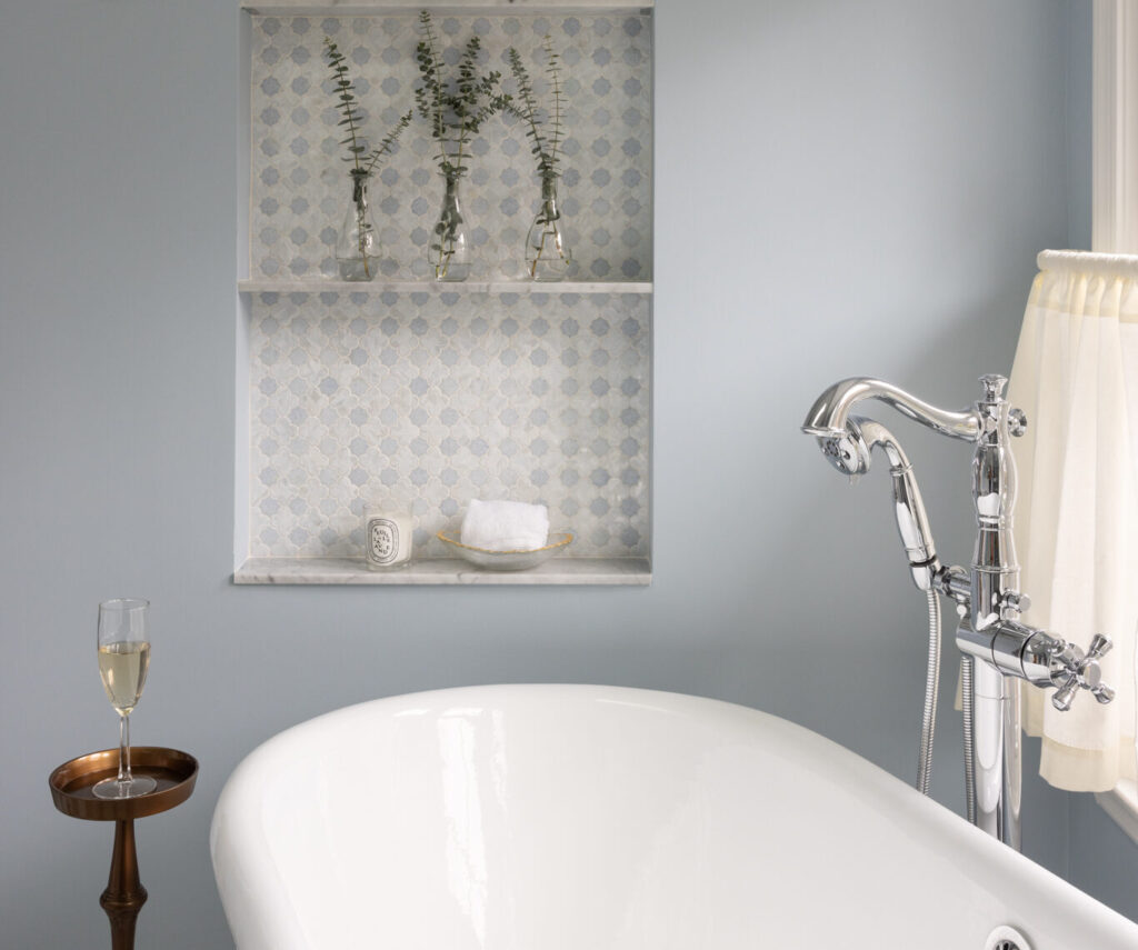 A bright remodeled bathroom with a freestanding tub, walk-in shower, blue walls, and built-in arched storage niches
