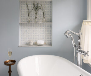 A bright remodeled bathroom with a freestanding tub, walk-in shower, blue walls, and built-in arched storage niches.